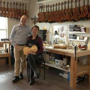 Samantha and Estefan, Owner showing music instrument repair shop